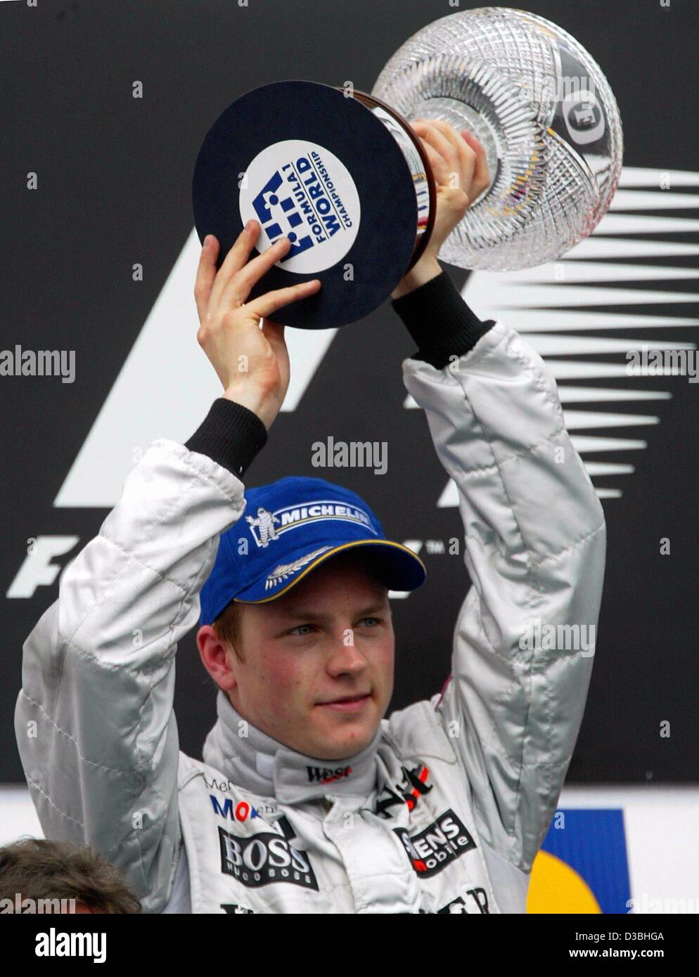 (Dpa) - El piloto de Fórmula Uno finlandés Kimi Raeikkoenen (McLaren-Mercedes) se levanta el trofeo alto arriba en el aire después de venir el segundo lugar en el Gran Premio de San Marino en la pista de carreras en Imola, Italia, 20 de abril de 2003. Con 32 puntos, Raeikkoenen momentáneamente ocupa el primer lugar en el ranking mundial de ch Foto de stock