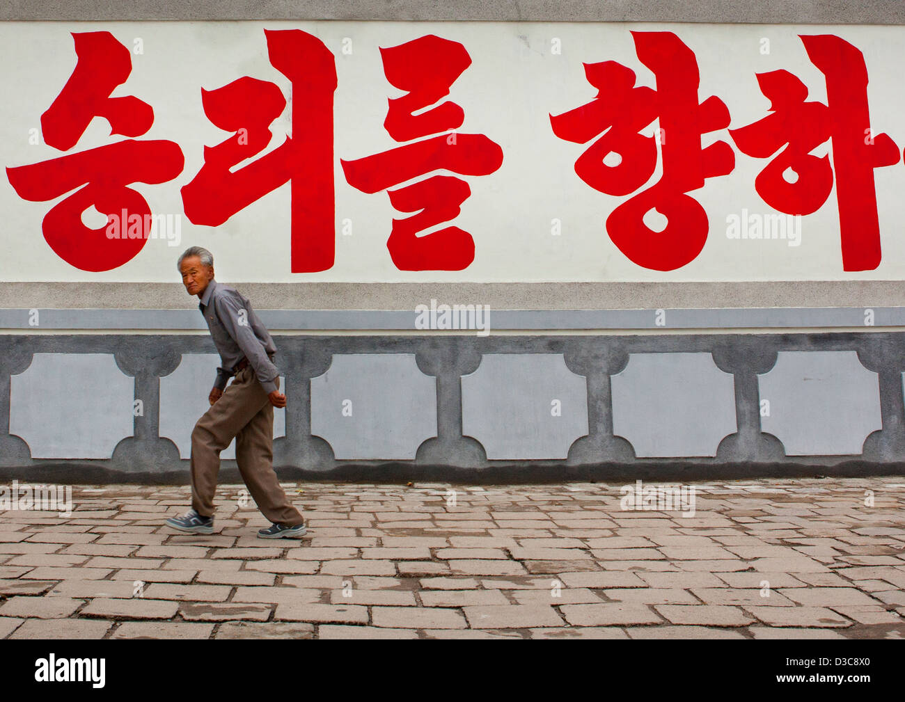 El hombre pasa delante de una valla publicitaria, Kaesong, Corea del Norte Foto de stock