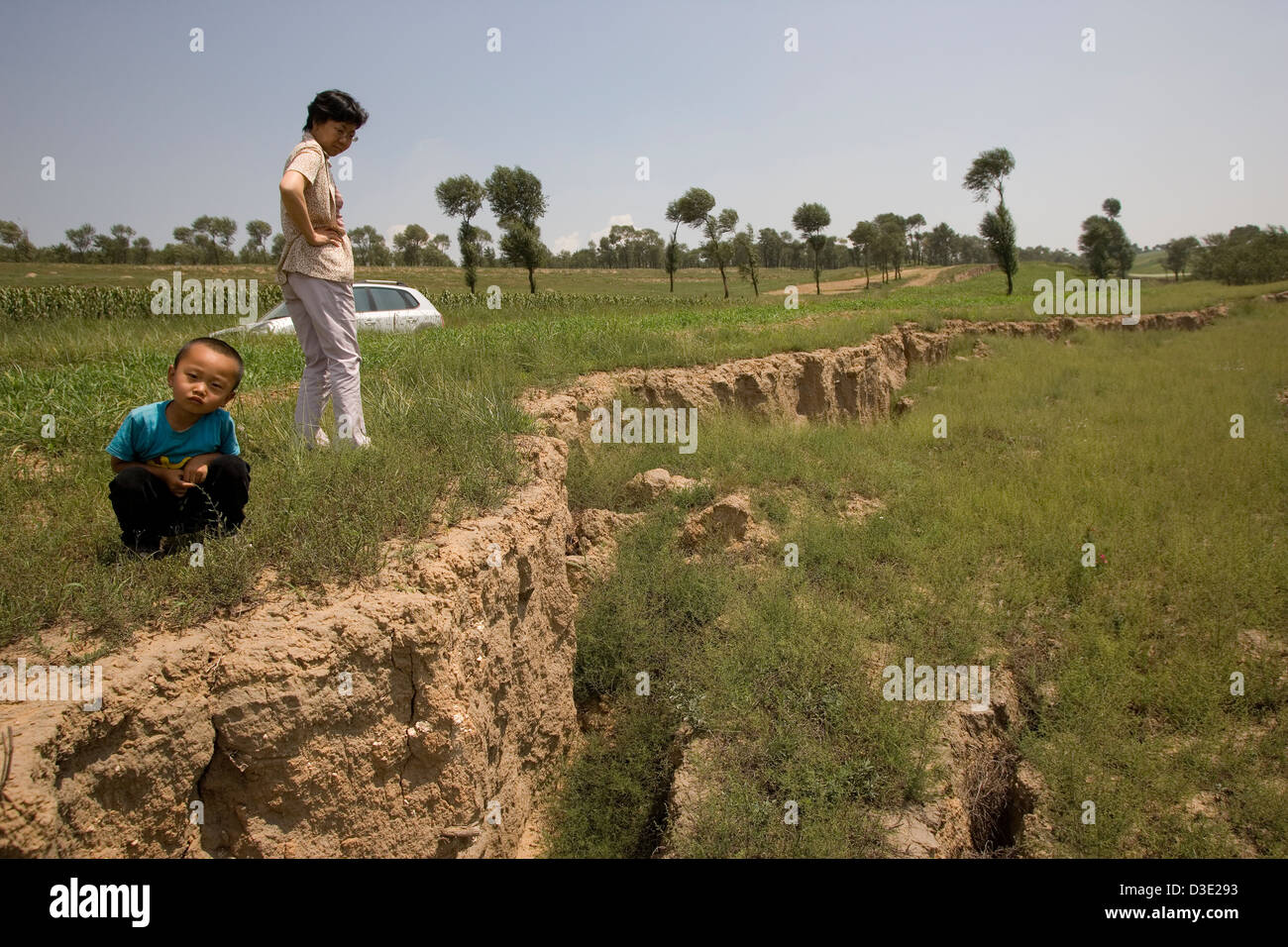 SHANG MAHUANGTOU Village, en la provincia china de Shanxi, agosto de 2007: un campesino y su hijo inspeccione la subsidencia de la tierra causada por la minería incontrolada Foto de stock