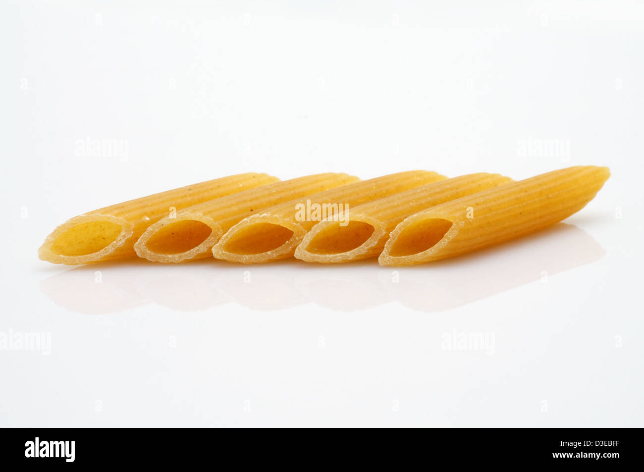 Este es un largo tubo hueco en forma de pasta rigatoni sobre fondo blanco. Foto de stock