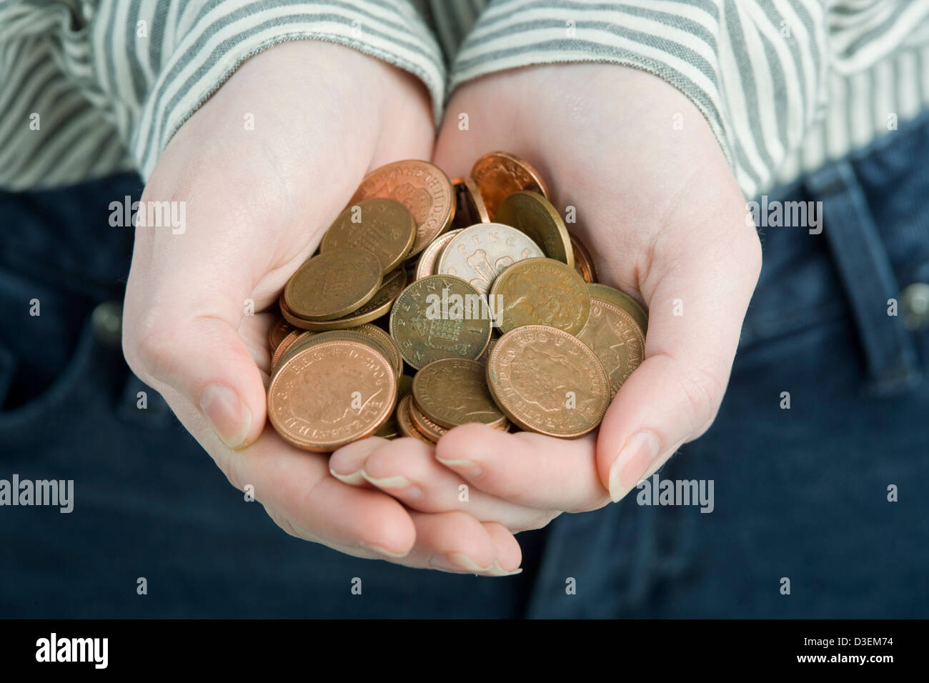 Ahuecada manos sosteniendo un montón de monedas de color bronce. Foto de stock