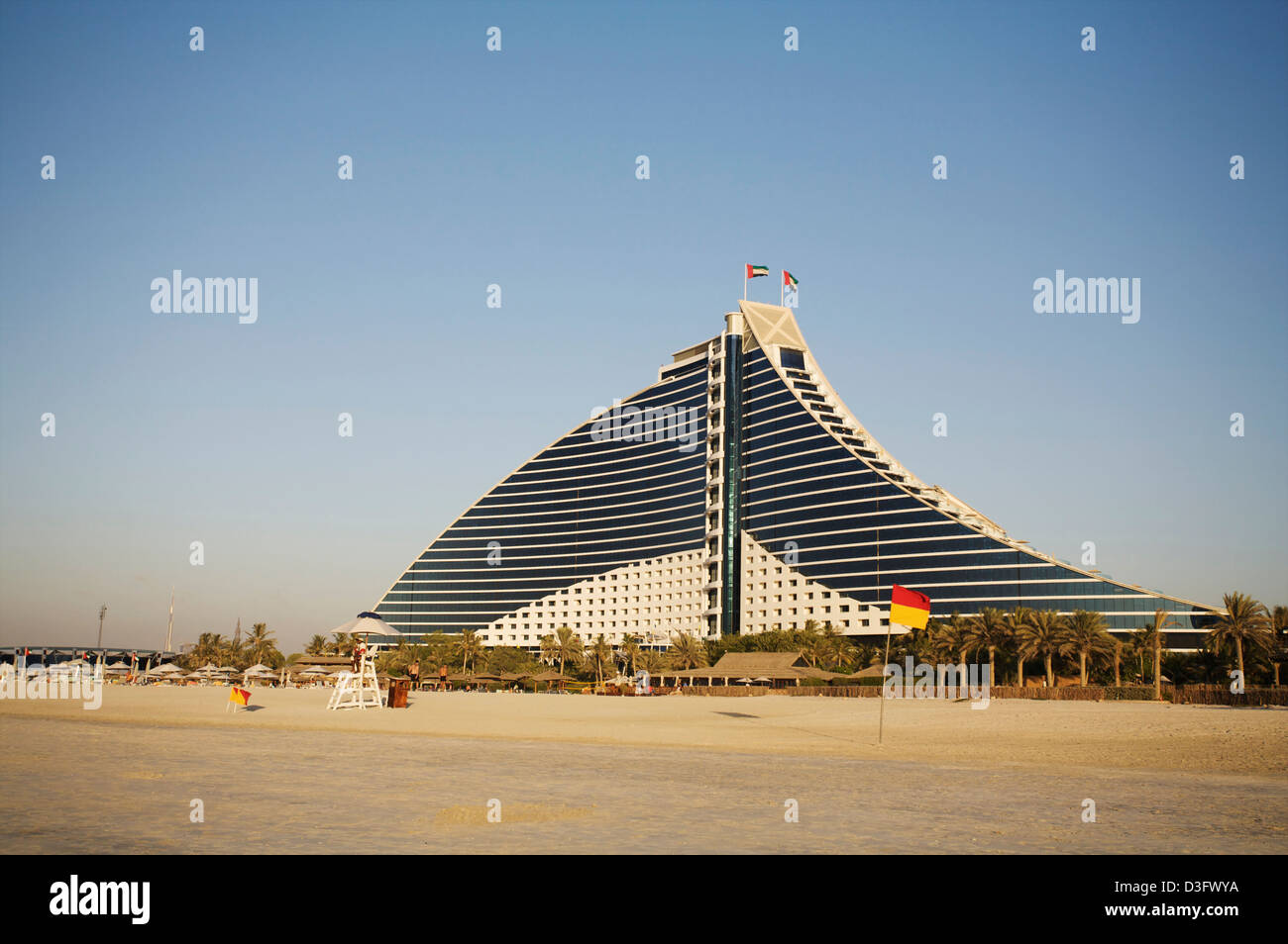 JUMEIRAH BEACH HOTEL visto desde la playa mientras el sol se pone delante de él. Foto de stock