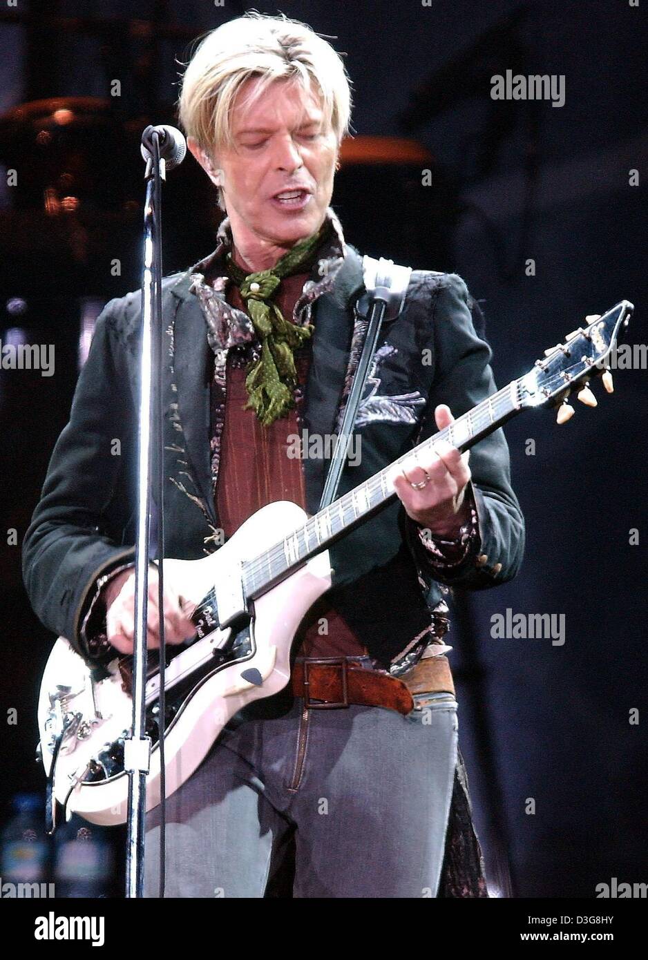 Dpa) - David Bowie está en un escenario frente a un micrófono y toca la  guitarra durante su concierto en el Color Line Arena de Hamburgo, Alemania,  el 16 de octubre de