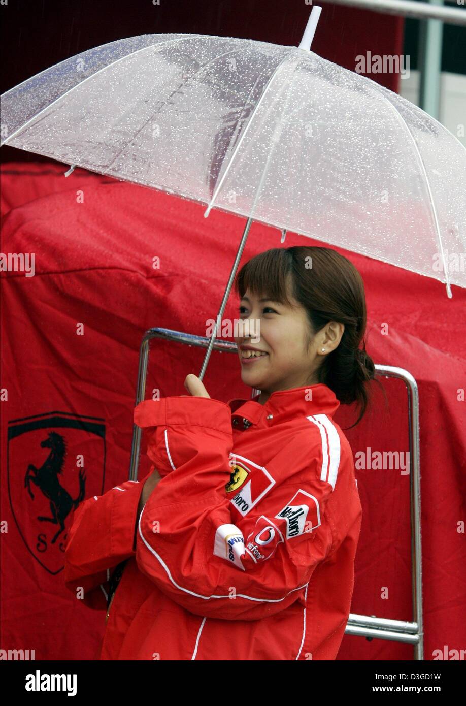 Dpa) - Una azafata de Ferrari con un "paraguas" en la lluvia durante capacitación gratuita en Suzuka International Racing Curso en Suzuka, Japón, el 8 de octubre de 2004. Debido a