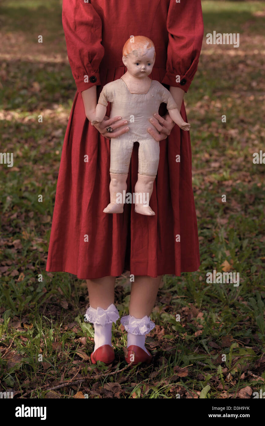 Una mujer en un rojo con una antigua muñeca de stock - Alamy