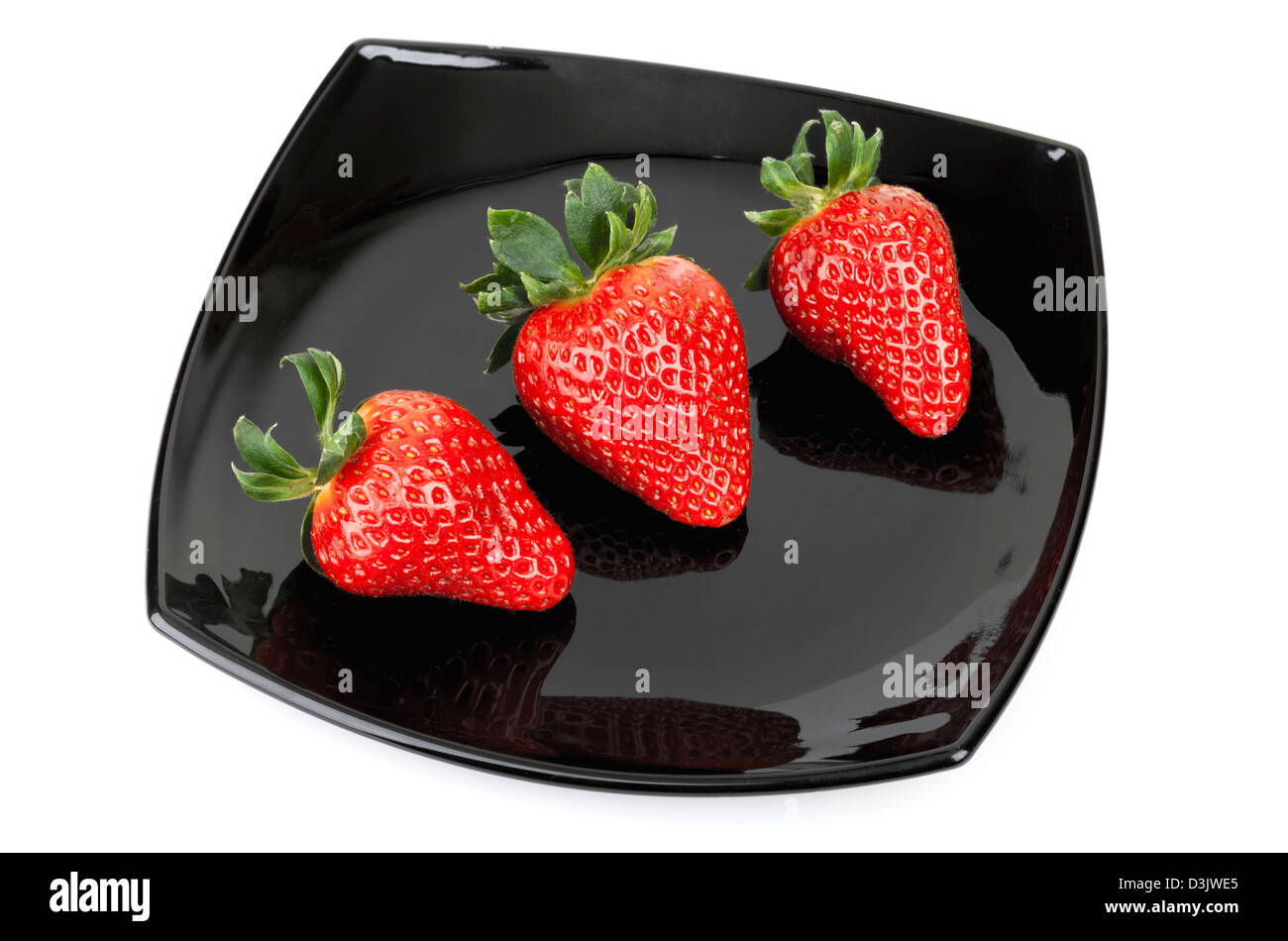 Tres fresas frescas sobre negro platillo aislado en blanco Foto de stock