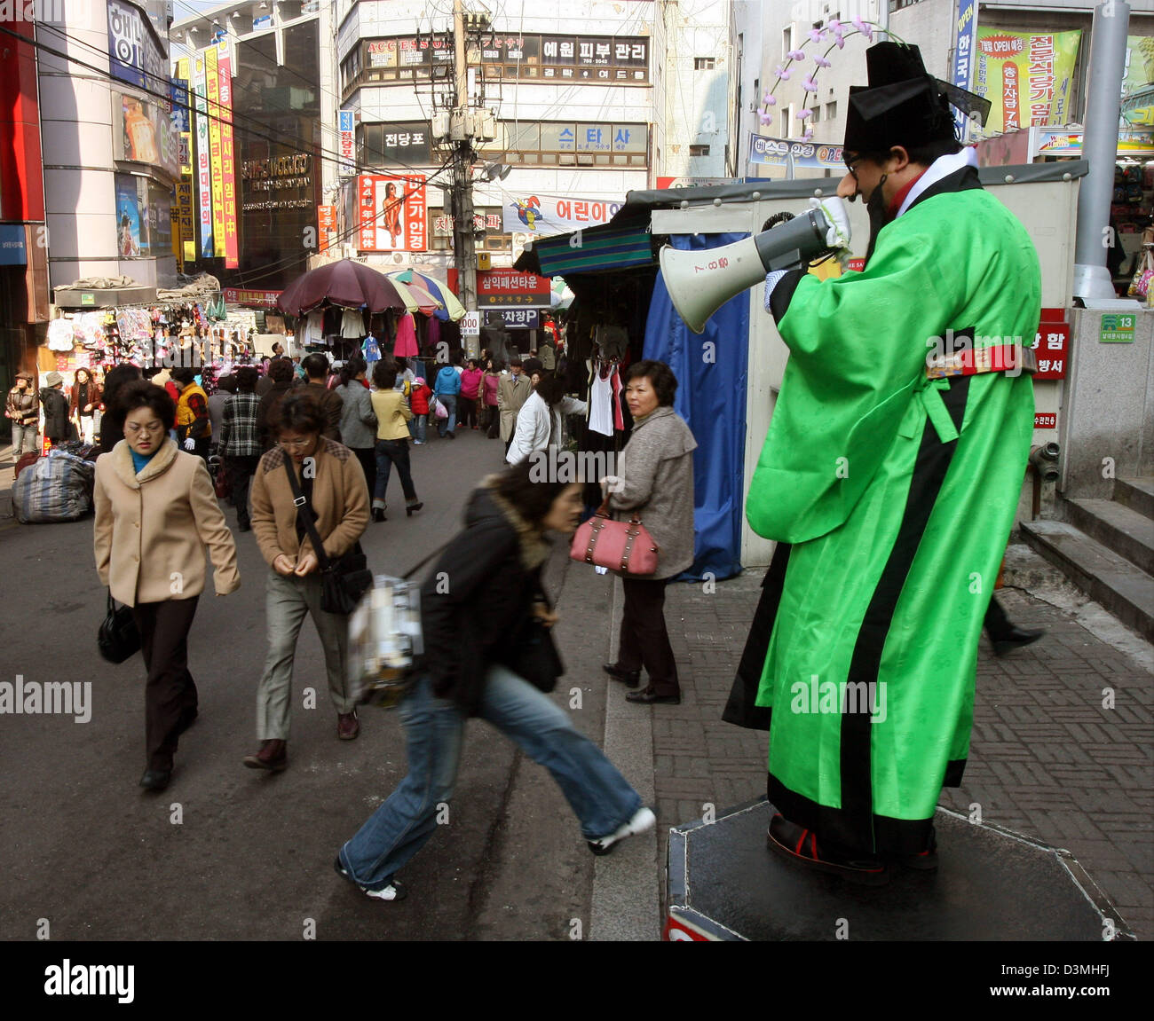 Un mountebarker vistiendo un traje tradicional con un megáfono intenta atraer clientes en un mercado en Seúl, Corea del Sur, el 20 de febrero de 2006. Foto: Tim Brakemeier Foto de stock