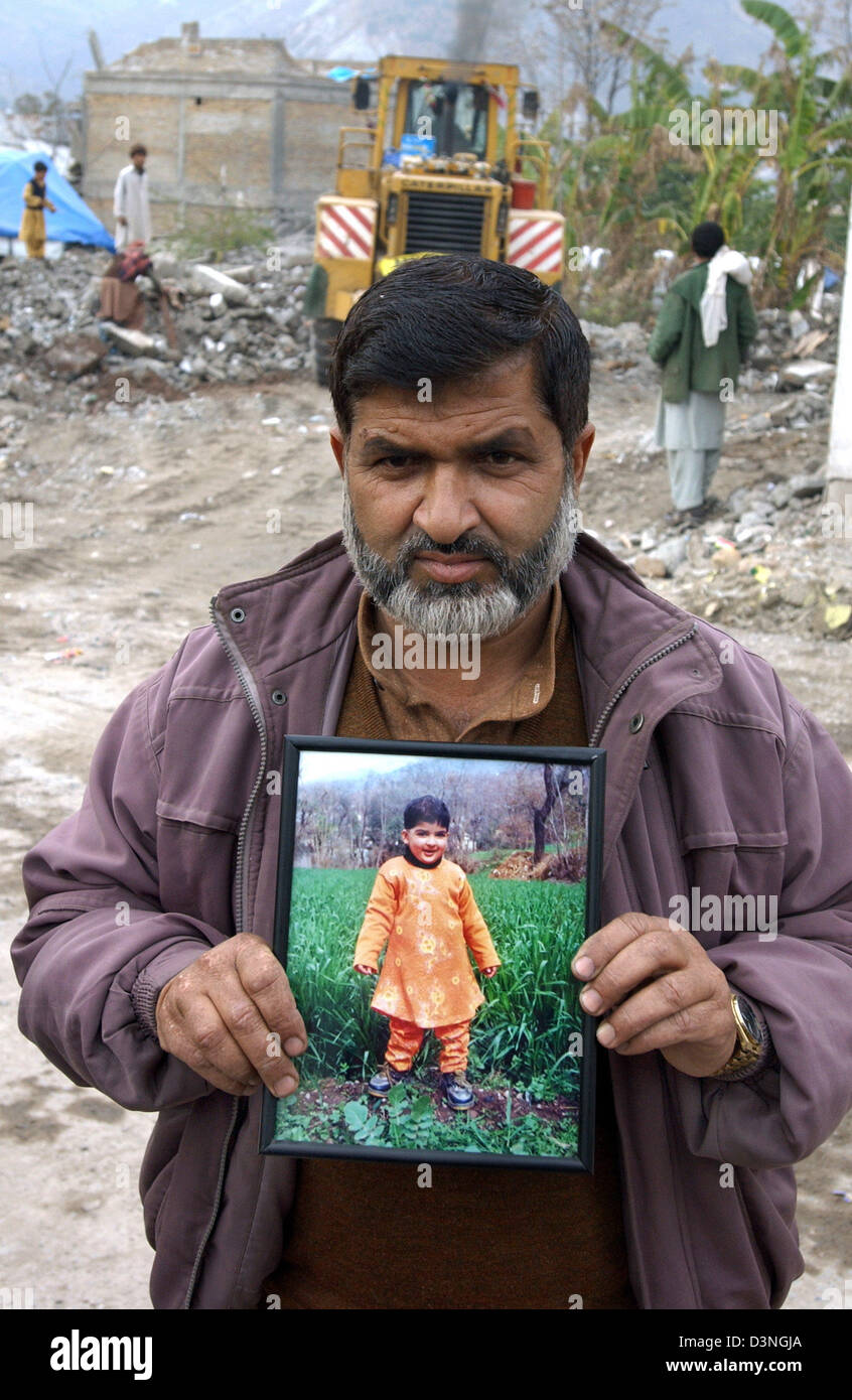 Un padre se muestra una imagen de su pequeña hija, quien fue enterrado por debries muerto después de que su escuela había colapsado en Muzaffarabad, Pakistán, Lunes, 30 de enero de 2006. En el fondo, una pala de bulldozer debries se quita. El noreste de la provincia de Cachemira, Pakistán había sido golpeada por un terremoto de intensidad de 7,6 sobre 8 de octubre de 2005. Casi 80.000 personas han sido asesinadas, más de Foto de stock