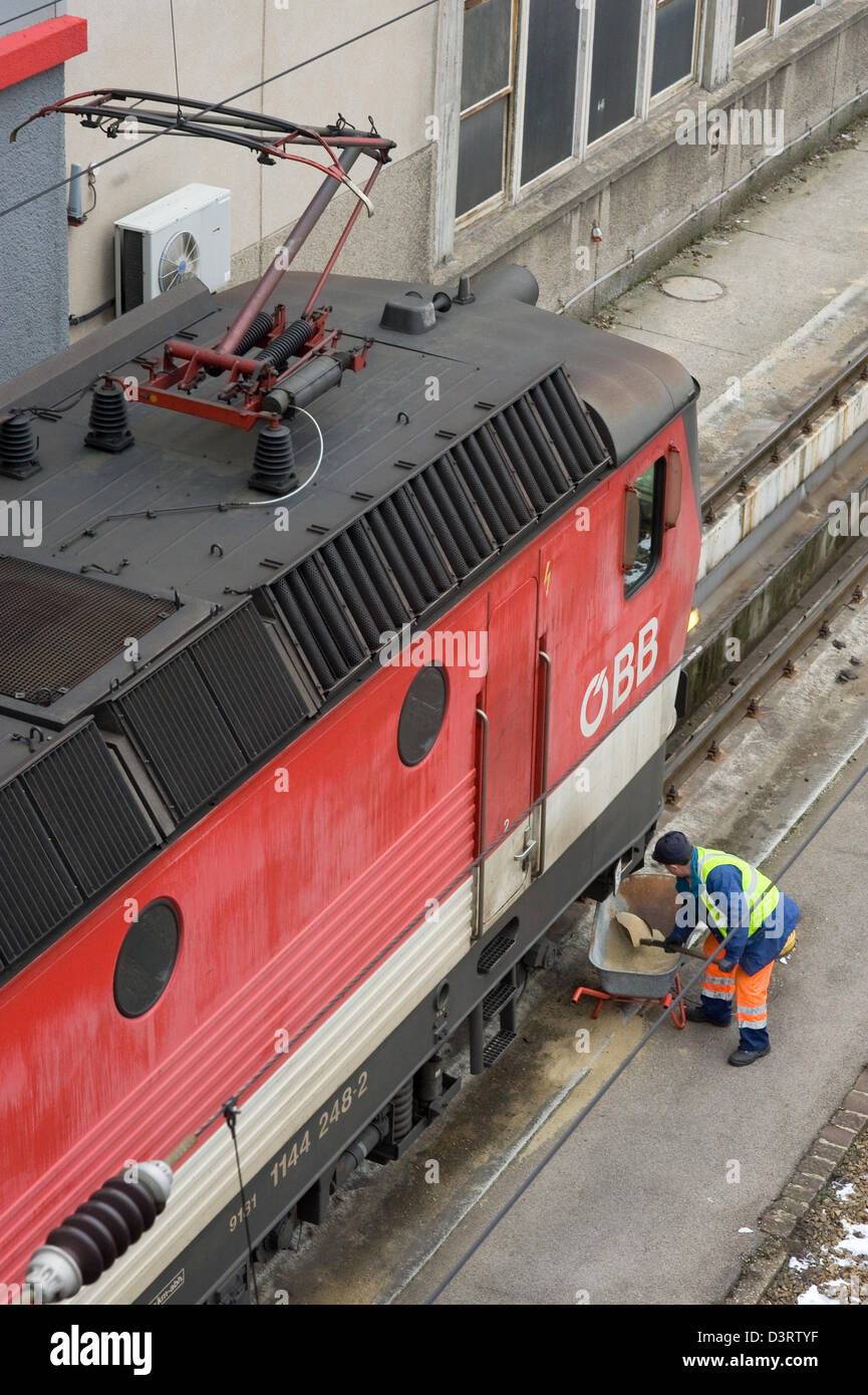 Viena, Austria, el empleado OEBB arrojando arena delante de una locomotora en las pistas Foto de stock