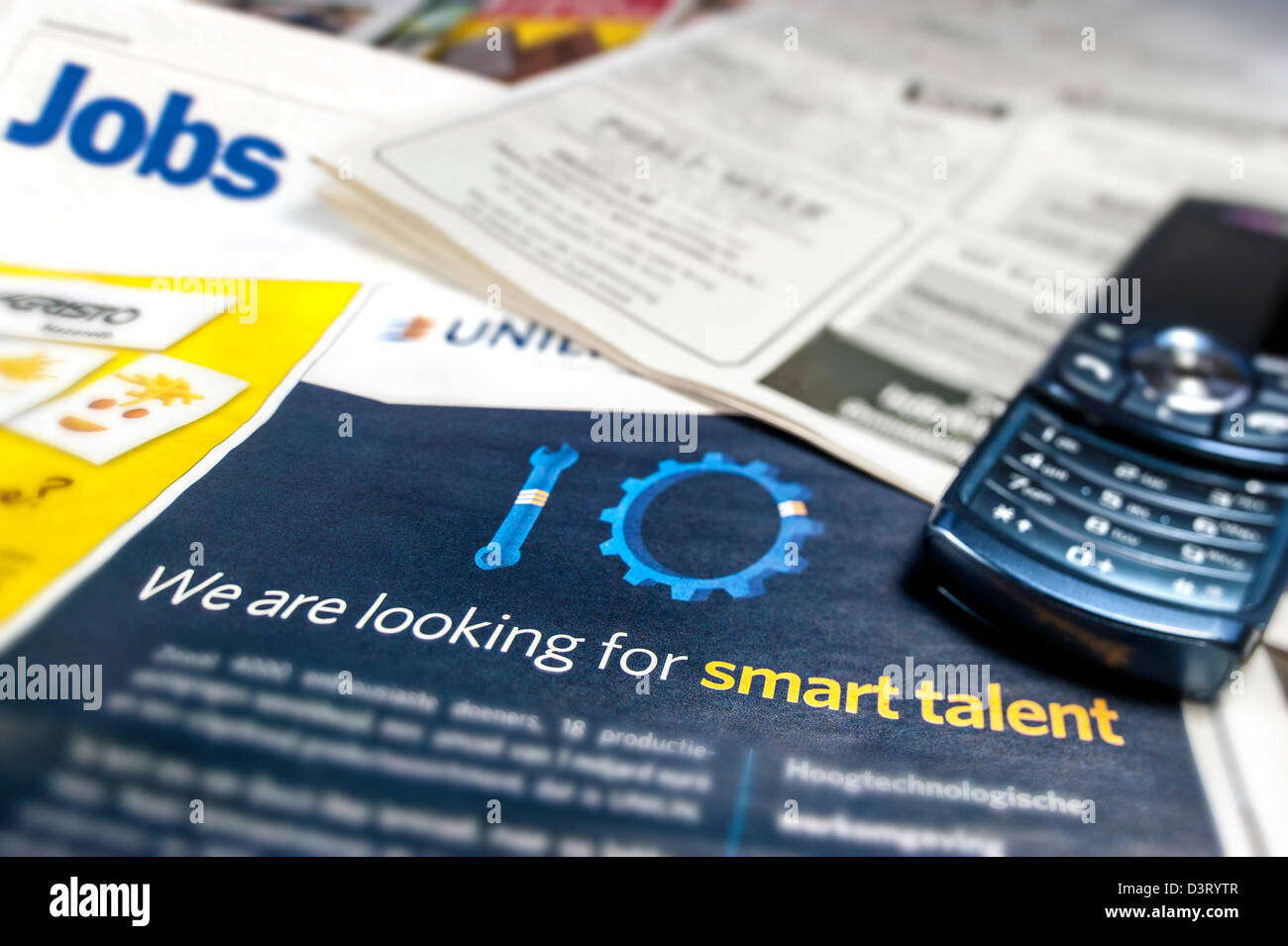 Teléfono celular y anuncios de empleos para los trabajadores desempleados de empleo página en los periódicos Foto de stock