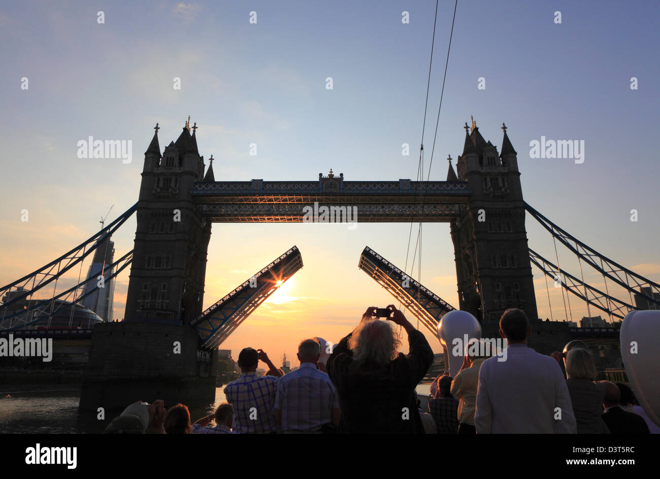 Turistas fotografiando Tower Bridge al atardecer desde un barco en el río Támesis Londres Inglaterra Reino Unido GB. Los turistas que toman una foto al atardecer. Foto de stock