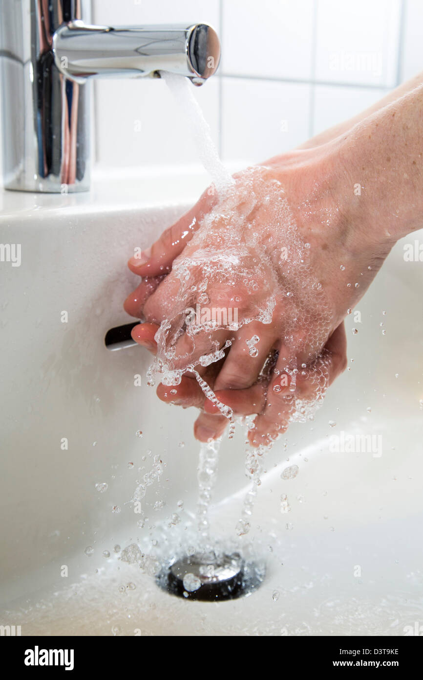 Persona es lavarse las manos con agua de un grifo en el cuarto de baño.  Imagen de símbolo para el despilfarro de agua Fotografía de stock - Alamy