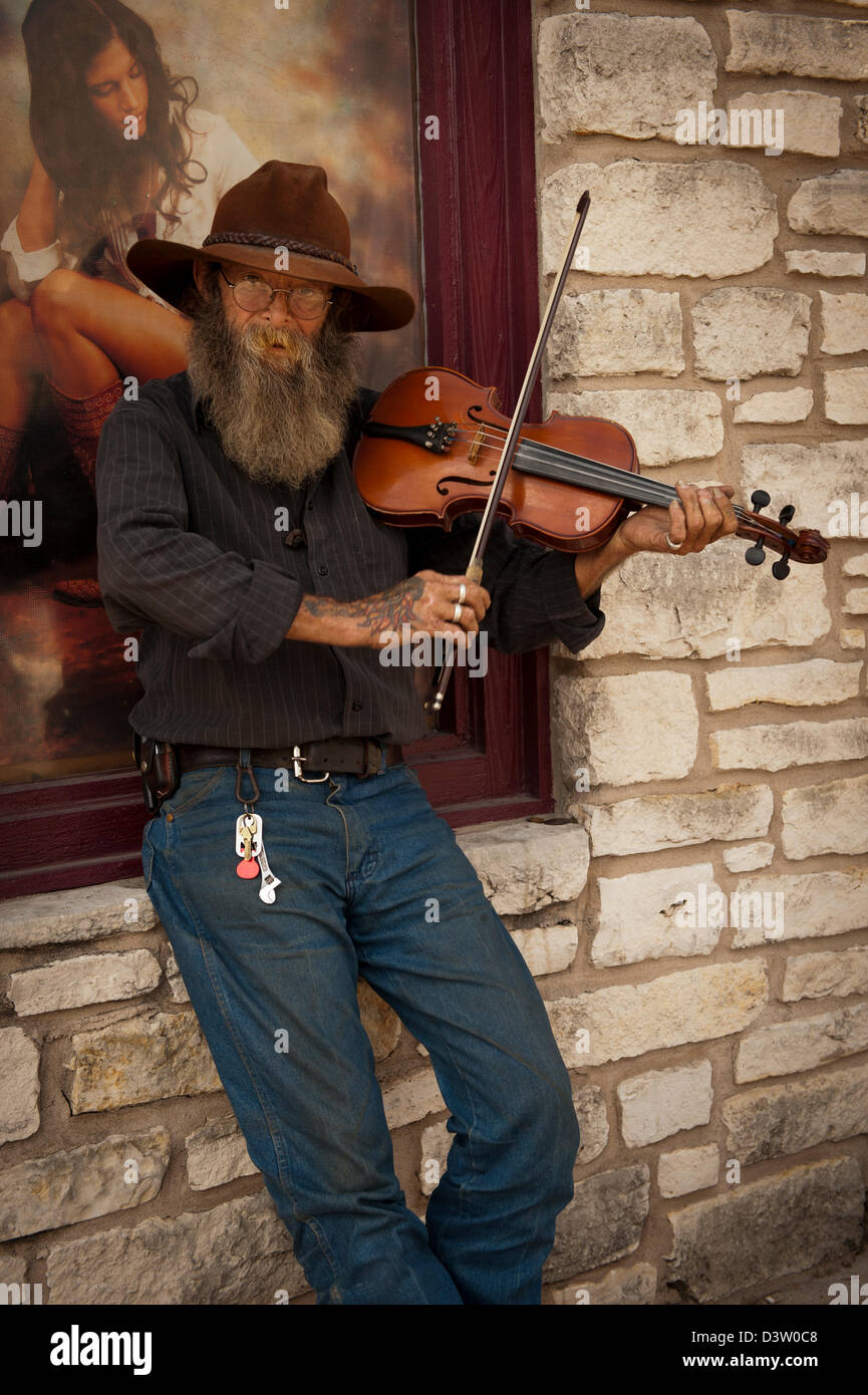 Fiddler de Texas con la barba y el sombrero floppy/violín toca su violín en la esquina de una calle. Foto de stock