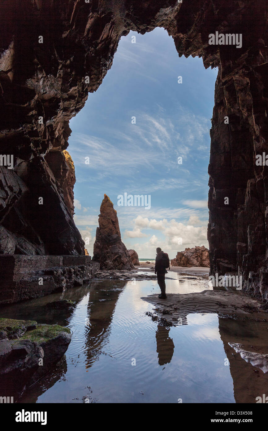 Roca de agujas con una persona de pie en la cueva Plemont, Jersey, Islas del Canal, REINO UNIDO Foto de stock