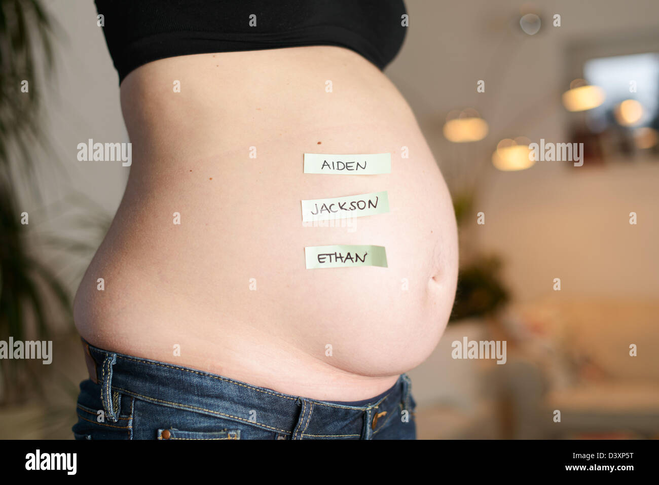 Los tres más populares English Boys' nombres están en un bebé el vientre de una mujer embarazada. Foto de stock