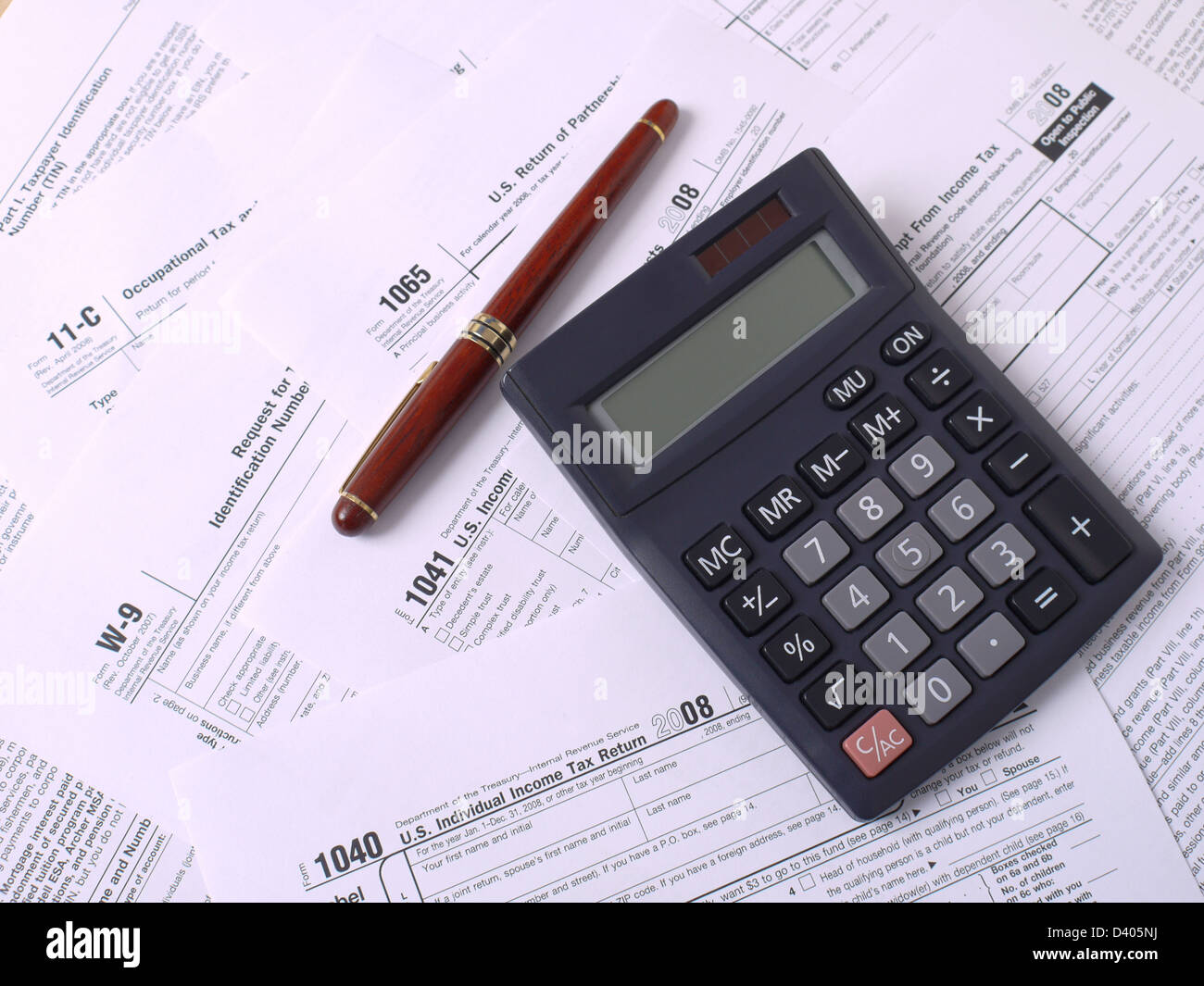Calculadora y bolígrafo de tinta poniendo en diversos formularios del impuesto sobre la renta americano Foto de stock