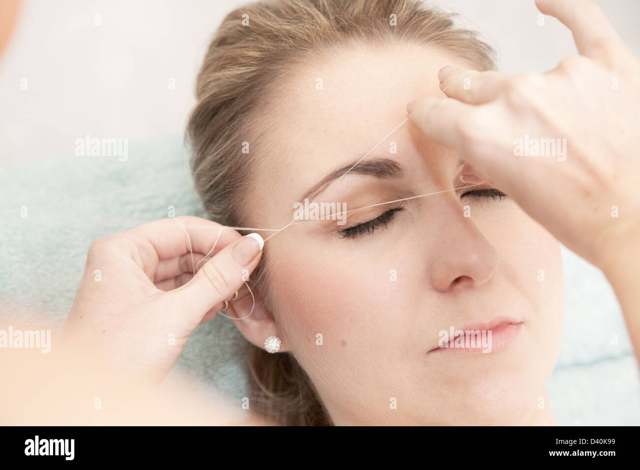 Mujer joven con sus cejas roscados, para eliminar el pelo no deseado. Esta técnica permite la conformación precisa relativamente sin dolor Foto de stock