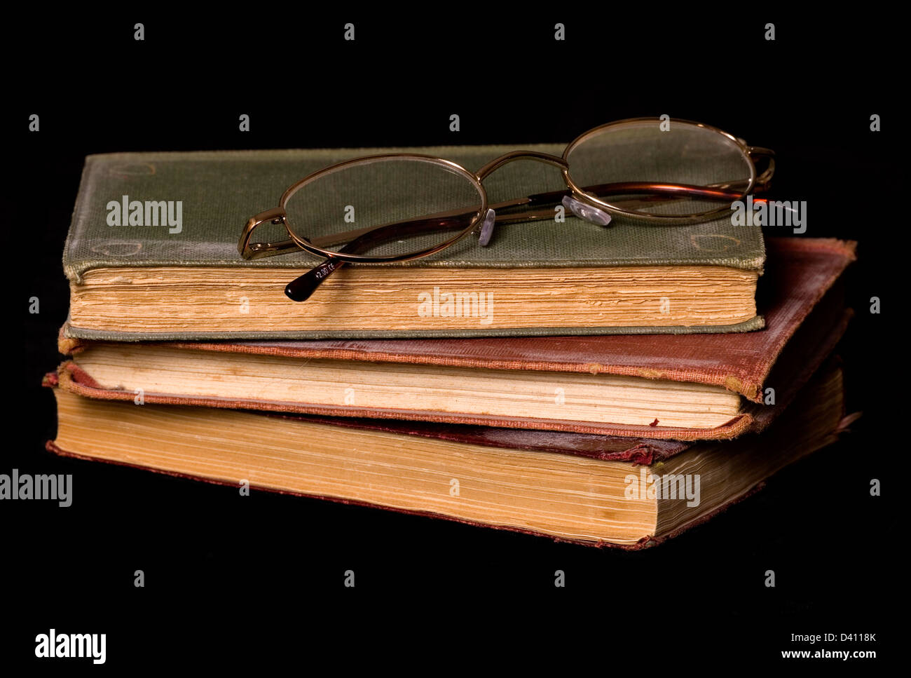 Libros antiguos y gafas de lectura sobre un fondo negro Foto de stock