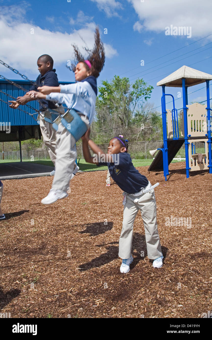7+ hembra negro empuja chica de raza mixta en swing en la escuela Foto de stock