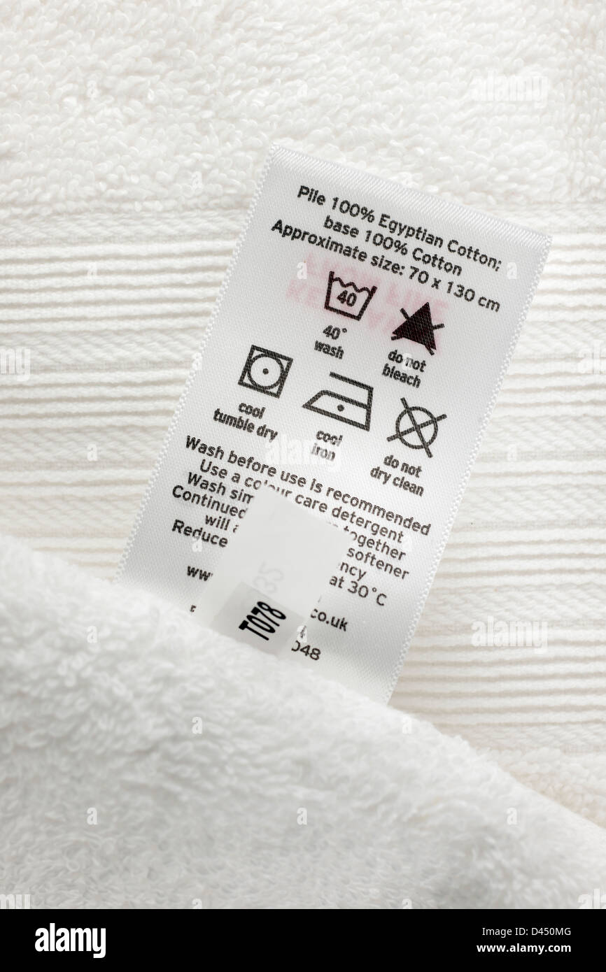 Cierre de un tacto suave y una toalla de baño blanco 100% algodón egipcio con etiqueta de instrucciones de lavado Foto de stock