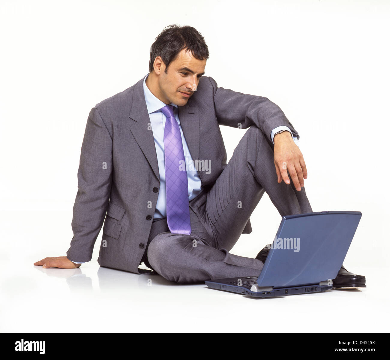 Stdio retrato de hombre de negocios palo atar el collar blanco traje de dos piezas y sentados en el suelo con su portátil. Foto de stock