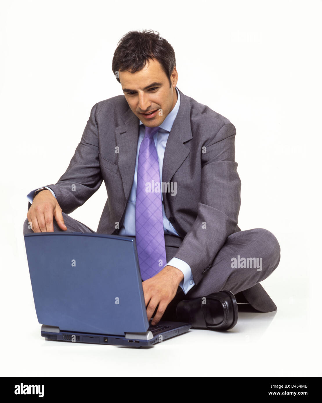 Stdio retrato de hombre de negocios palo atar el collar blanco traje de dos piezas y sentados en el suelo con su portátil. Foto de stock