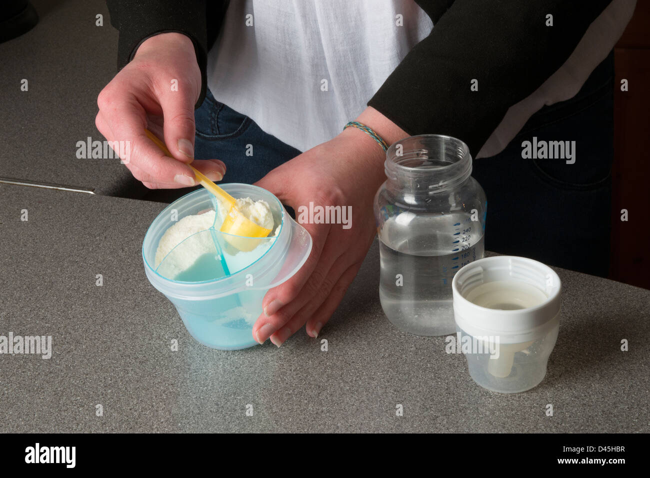 Las manos del joven madre preparar la bebida de leche en polvo para su bebé Foto de stock