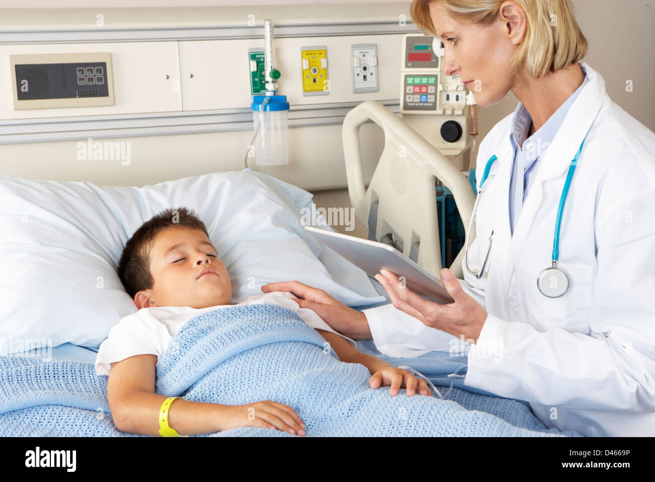 Doctor utilizando el Bloc de notas digital mientras visita paciente infantil Foto de stock