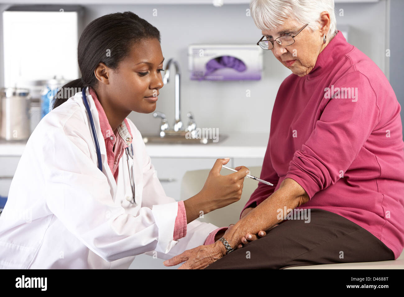 Doctor dando Senior femenino de inyección del paciente Foto de stock