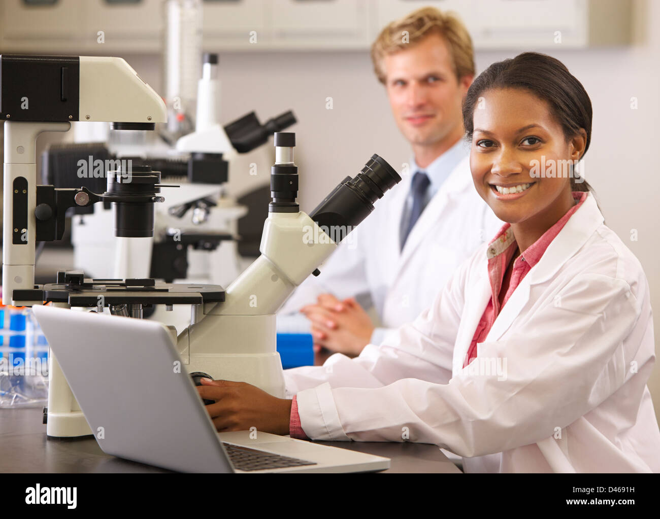 Varón y hembra los científicos usando microscopios en el laboratorio Foto de stock