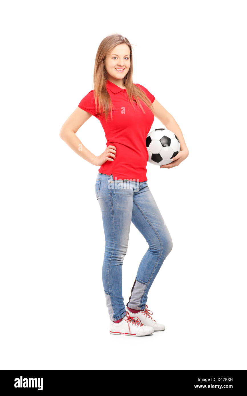 Longitud total retrato de una joven sonriente sosteniendo un balón de fútbol femenino aislado sobre fondo blanco. Foto de stock