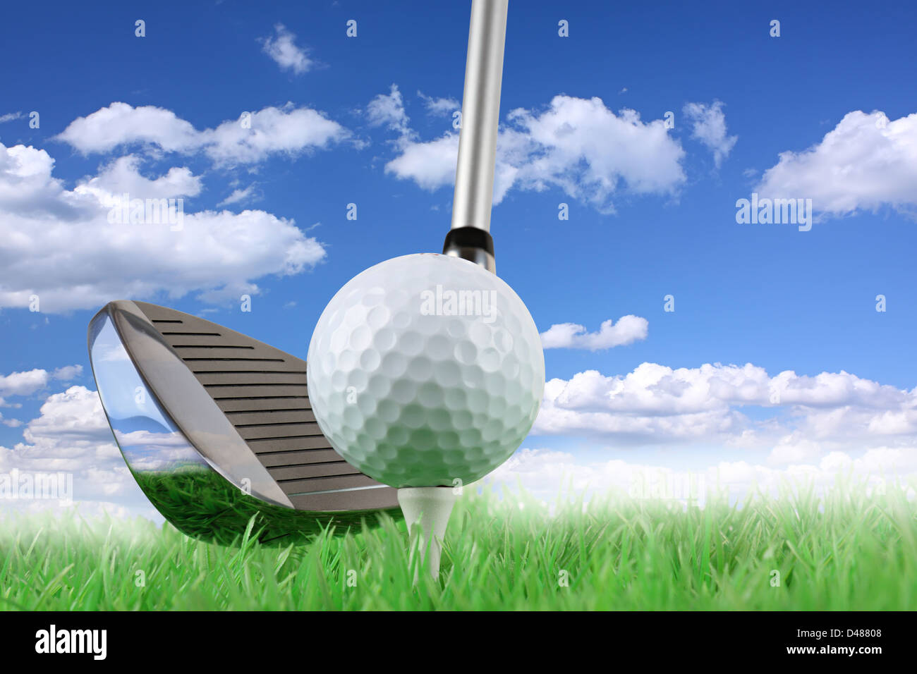 Club de golf con bola y tee de verde delante de azul cielo nublado Foto de stock