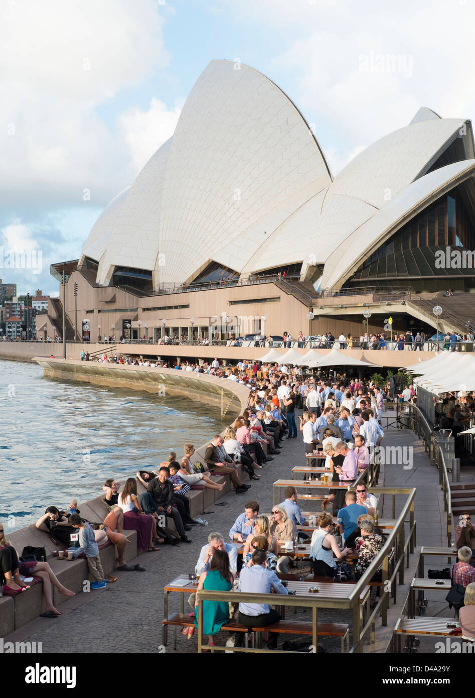Muchas personas bebiendo en la noche en los bares junto al puerto de Sydney Opera House en Australia Foto de stock