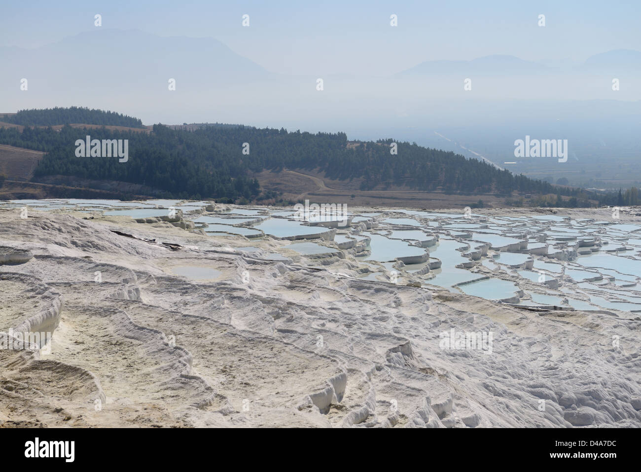 Seco y lleno de agua de manantial mineral de carbonato de calcio de travertino terrazas con montañas de Denizli Pamukkale en Turquía Foto de stock