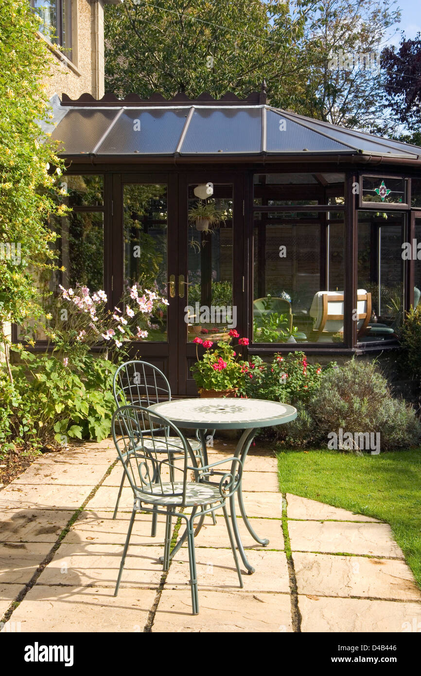 Jardines del Reino Unido. Un pequeño patio, mesa y sillas de jardín fuera de un conservatorio. Foto de stock
