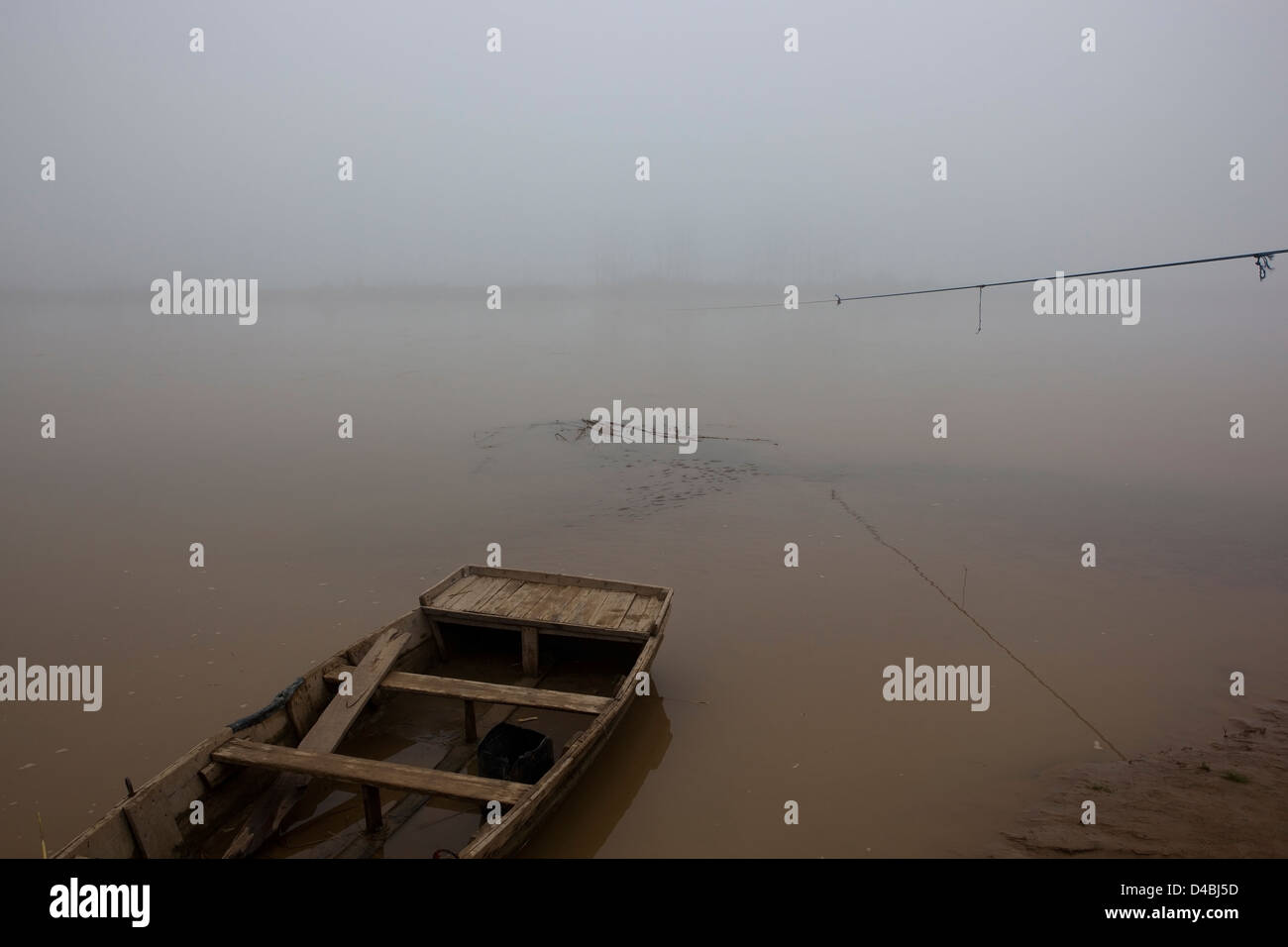 Un día brumoso en el río Beas con un pequeño barco de madera y cuerda en el Punjab, India Foto de stock