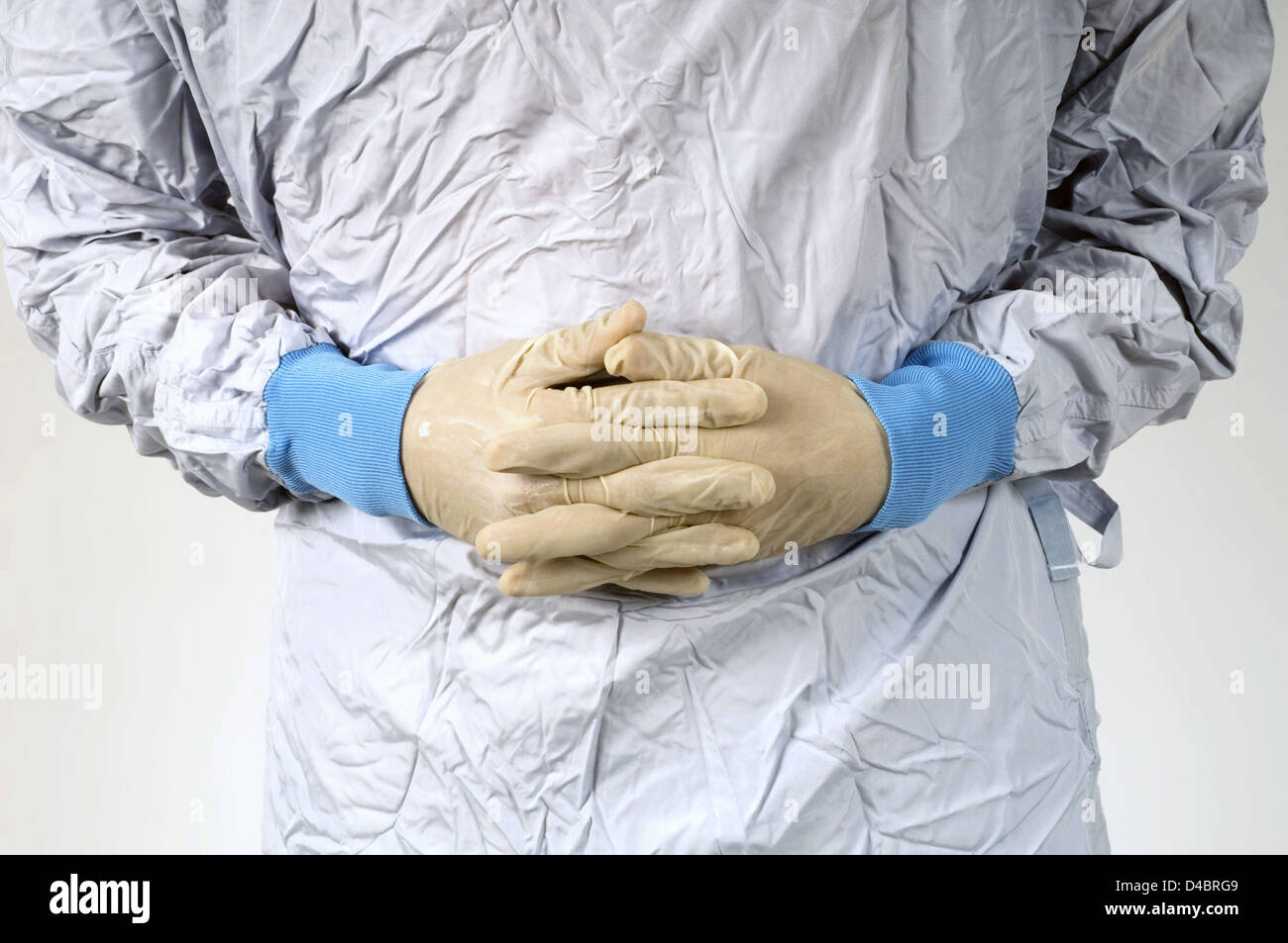 Cirujano estrechando manos enguantadas en frente de su estómago, sección intermedia Foto de stock