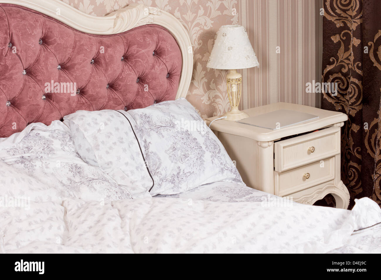 Un lujo romántico dormitorio detalles interiores con una ornamentada  acolchado cabecero rosa tapizadas con botones y elegante ropa de cama  estampada Fotografía de stock - Alamy