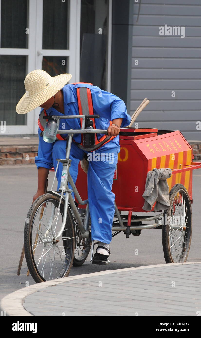 Una carretera sweeper es retratada con su bicicleta en Beijing, China, 10  de agosto de 2008. Debido a los Juegos Olímpicos de 2008, numerosos  barredoras asegúrese de que Pekín es una ciudad