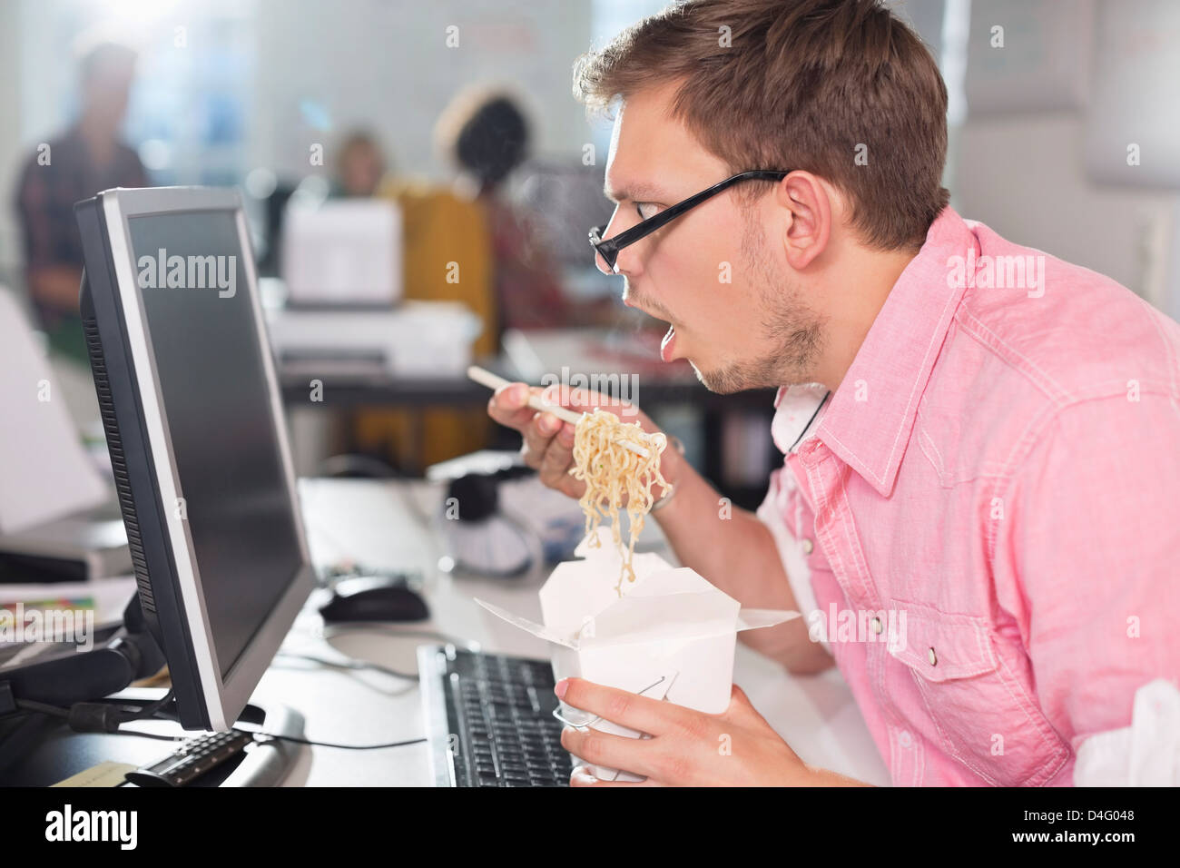 Empresario comiendo comida china en el escritorio Foto de stock