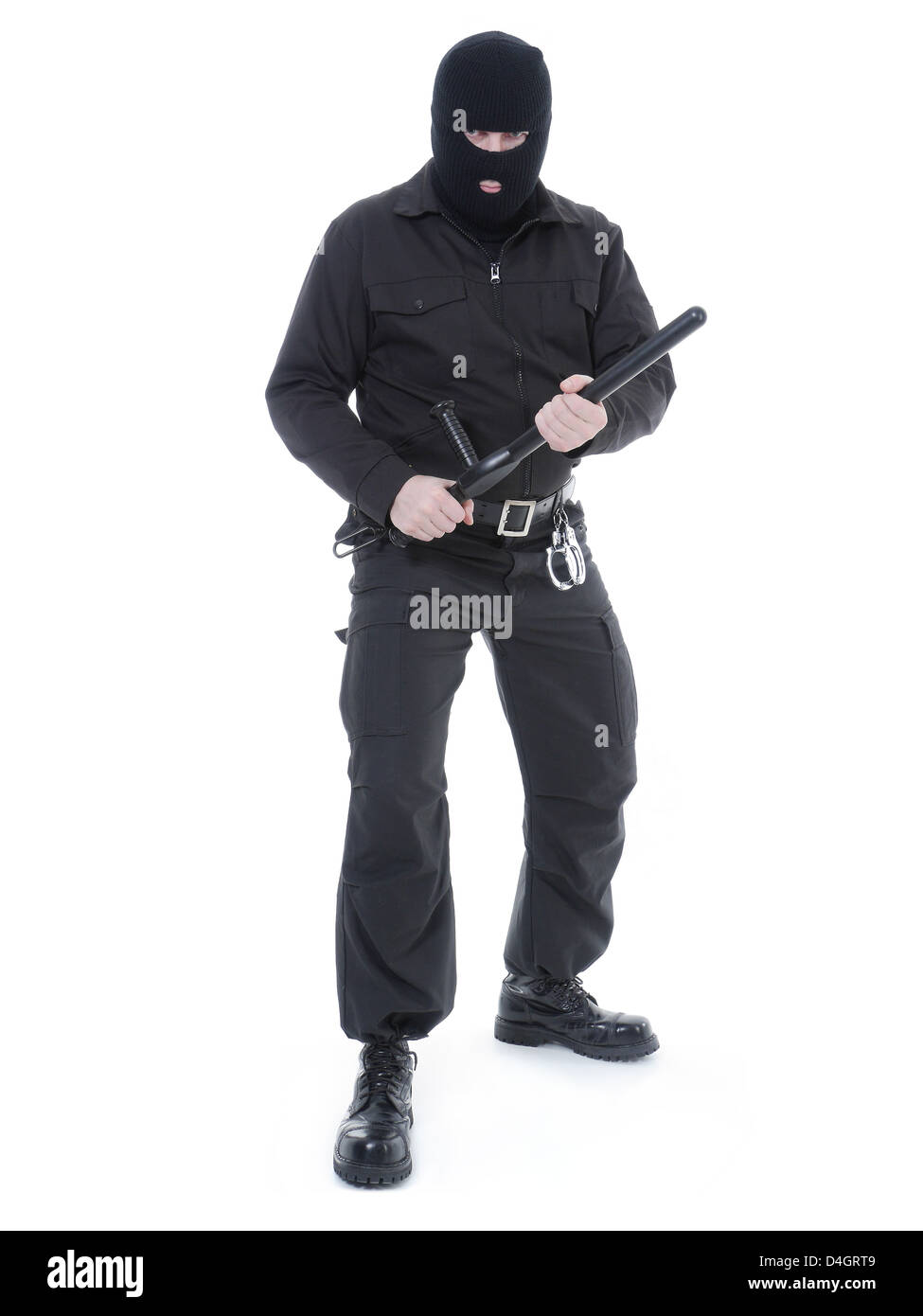 La policía antiterrorista guy vistiendo uniforme negro y máscara negra sujetando firmemente el club policial en ambas manos, listo para la acción Foto de stock