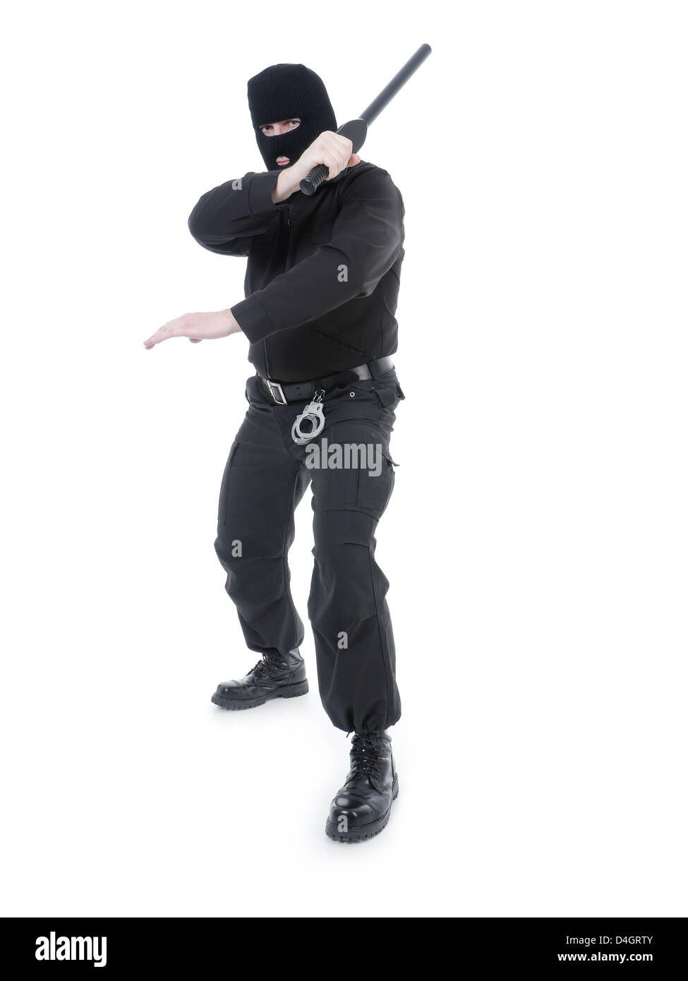 La policía antiterrorista guy vistiendo uniforme negro y máscara negra sujetando firmemente el club policial en una mano levantada en el aire Foto de stock