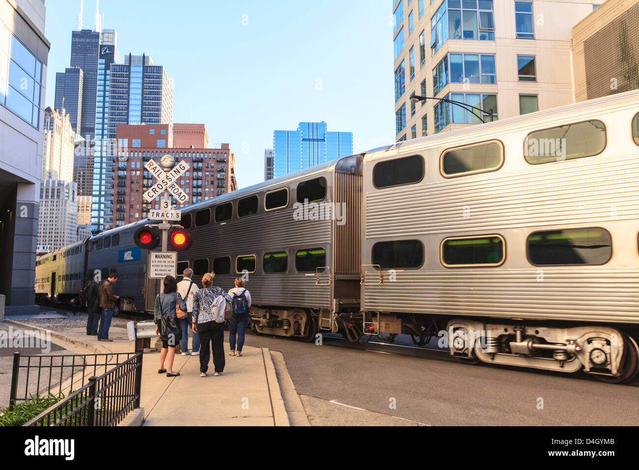 Metra tren pasa peatones en un cruce ferroviario abierto, el centro de Chicago, Illinois, EE.UU. Foto de stock