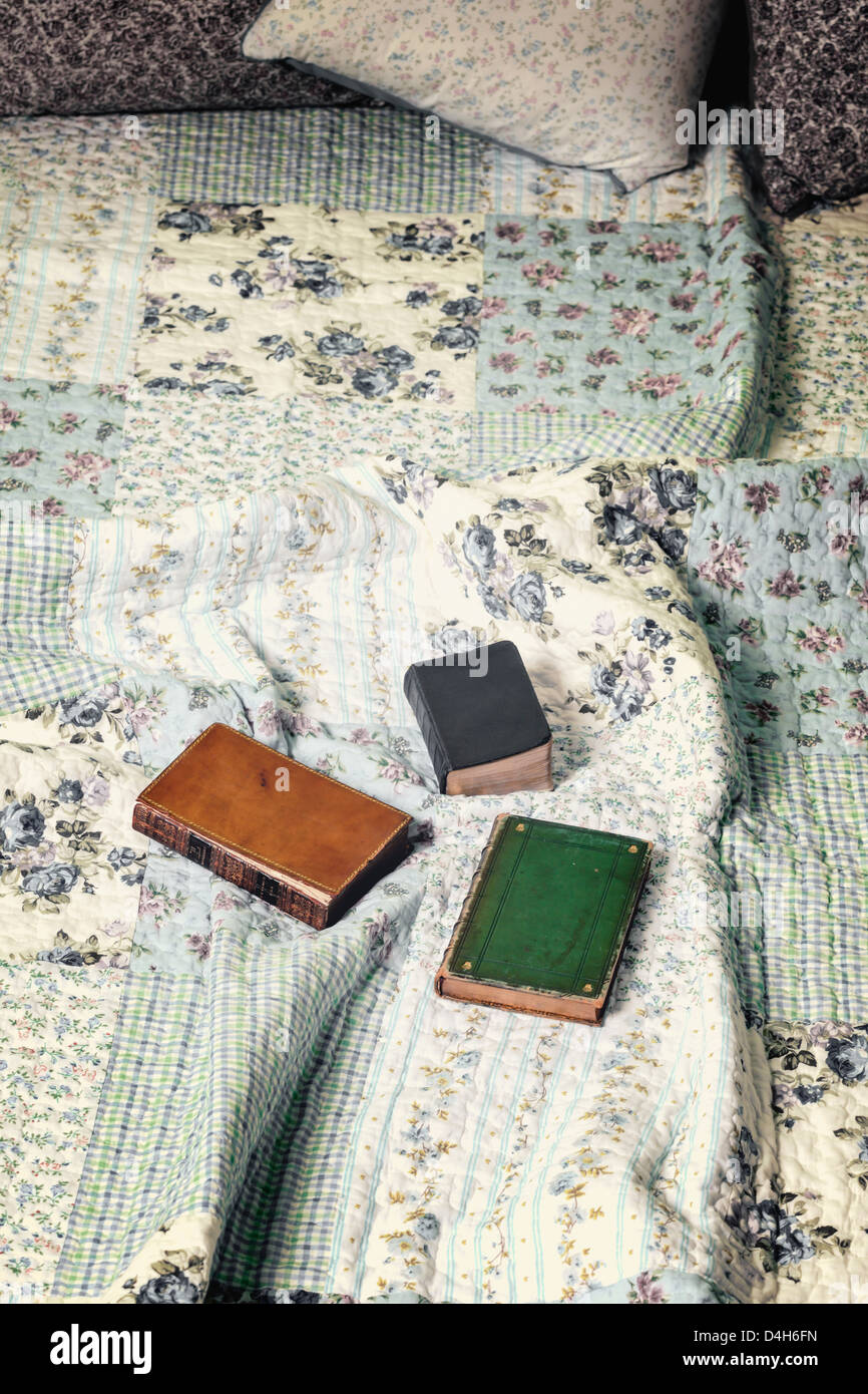 Tres libros antiguos en una cama vintage Foto de stock