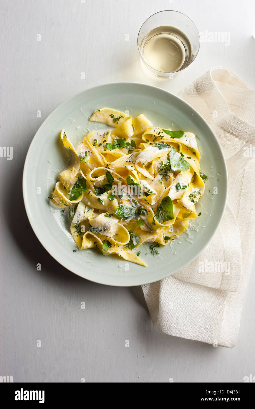 Un plato de pasta pappardelle con crema de requesón, baby de espinacas frescas, hierbas y pimienta negra. Foto de stock