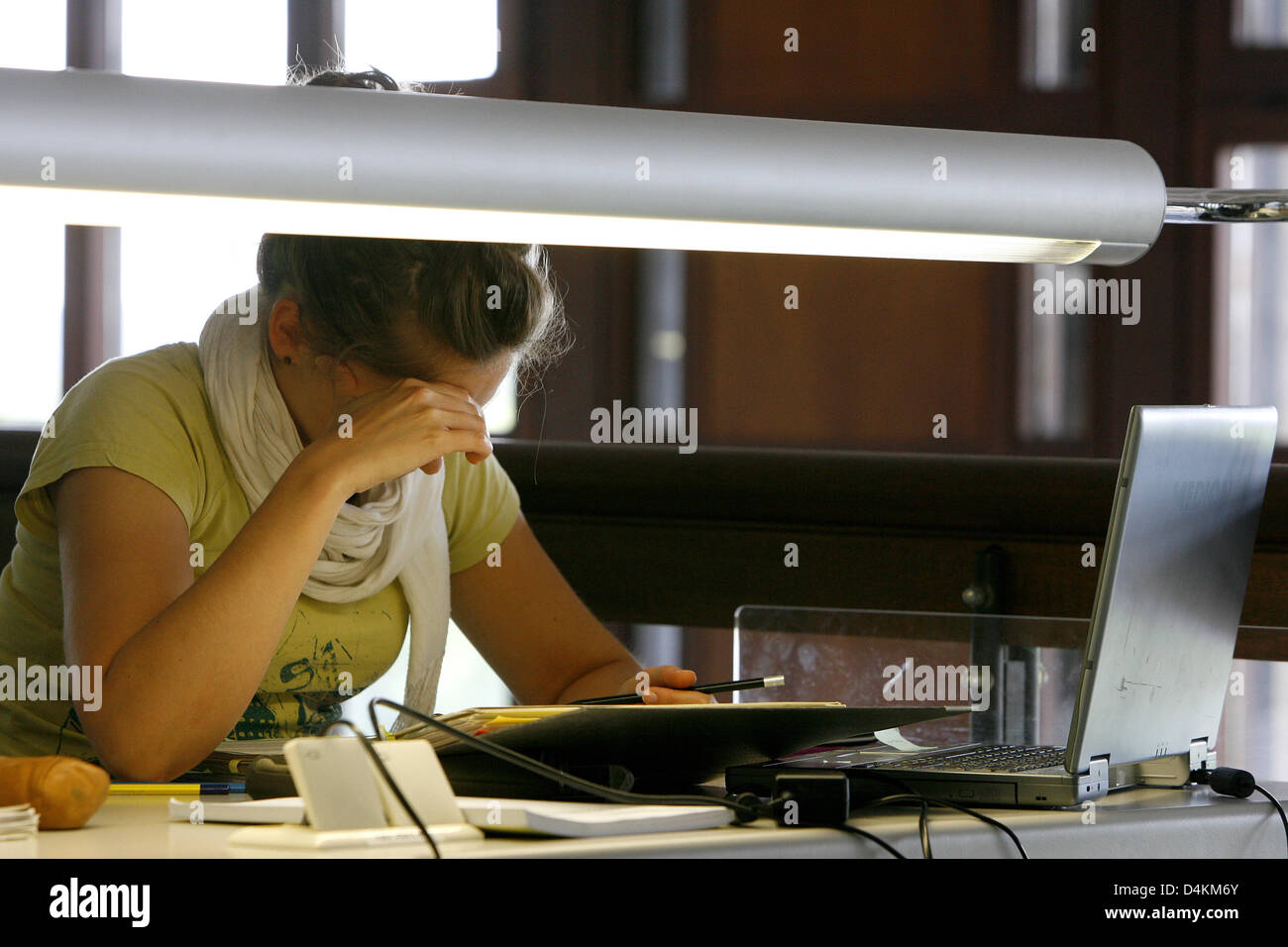 Una estudiante estudios concentratedly sobre un escritorio en la biblioteca de la Universidad de Würzburg, Alemania, 04 de mayo de 2009. Foto: Daniel Karmann Foto de stock