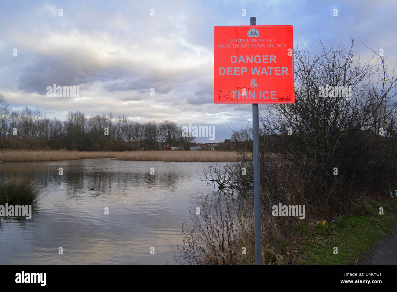 Señal de advertencia de aguas profundas y una fina capa de hielo por pond Yorkshire, Reino Unido Foto de stock