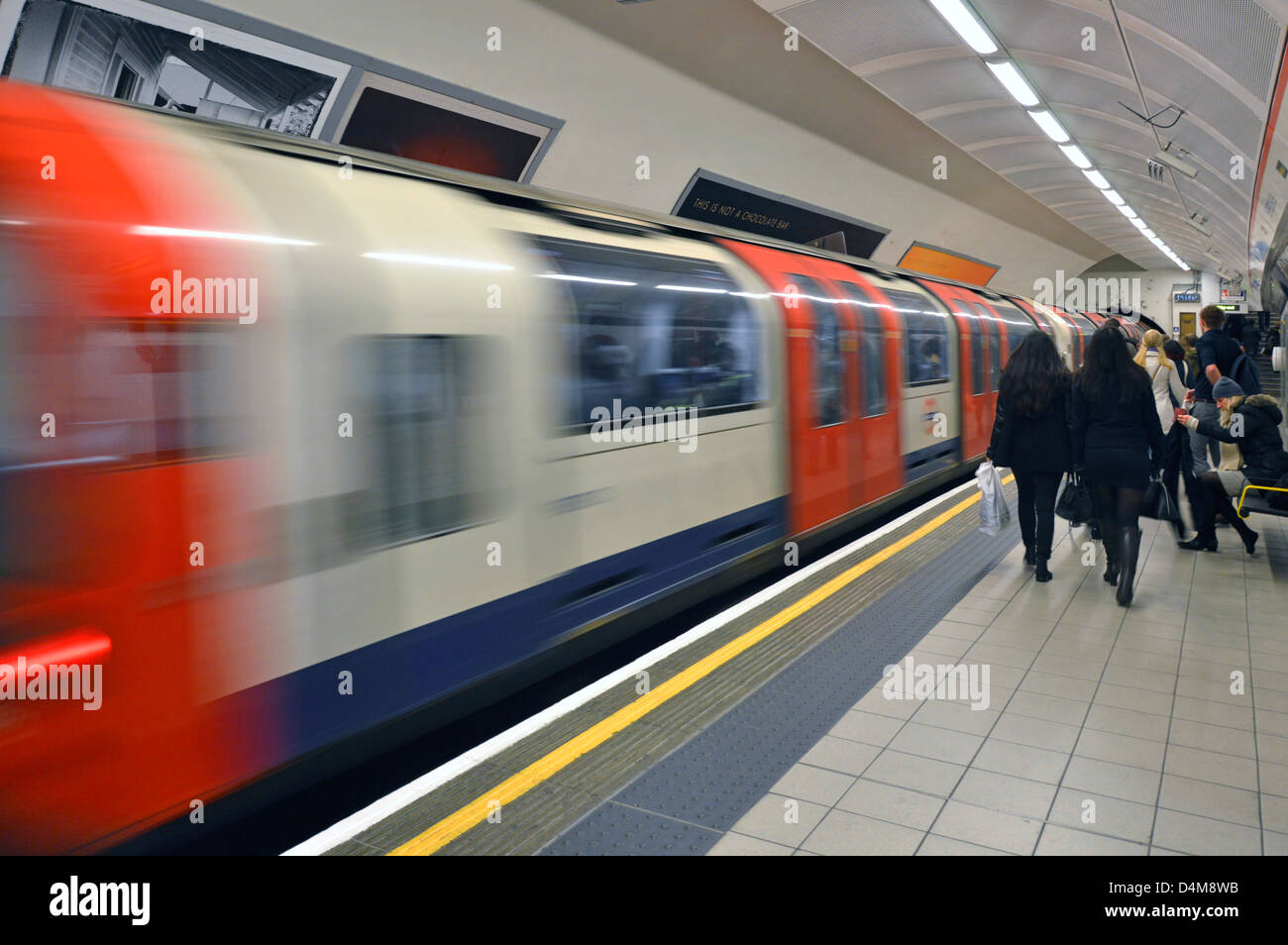 Metro de la línea central de metro de Londres estación de tren tren que sale la gente en la plataforma con motion blur Shepherds Bush en el oeste de Londres Inglaterra Foto de stock