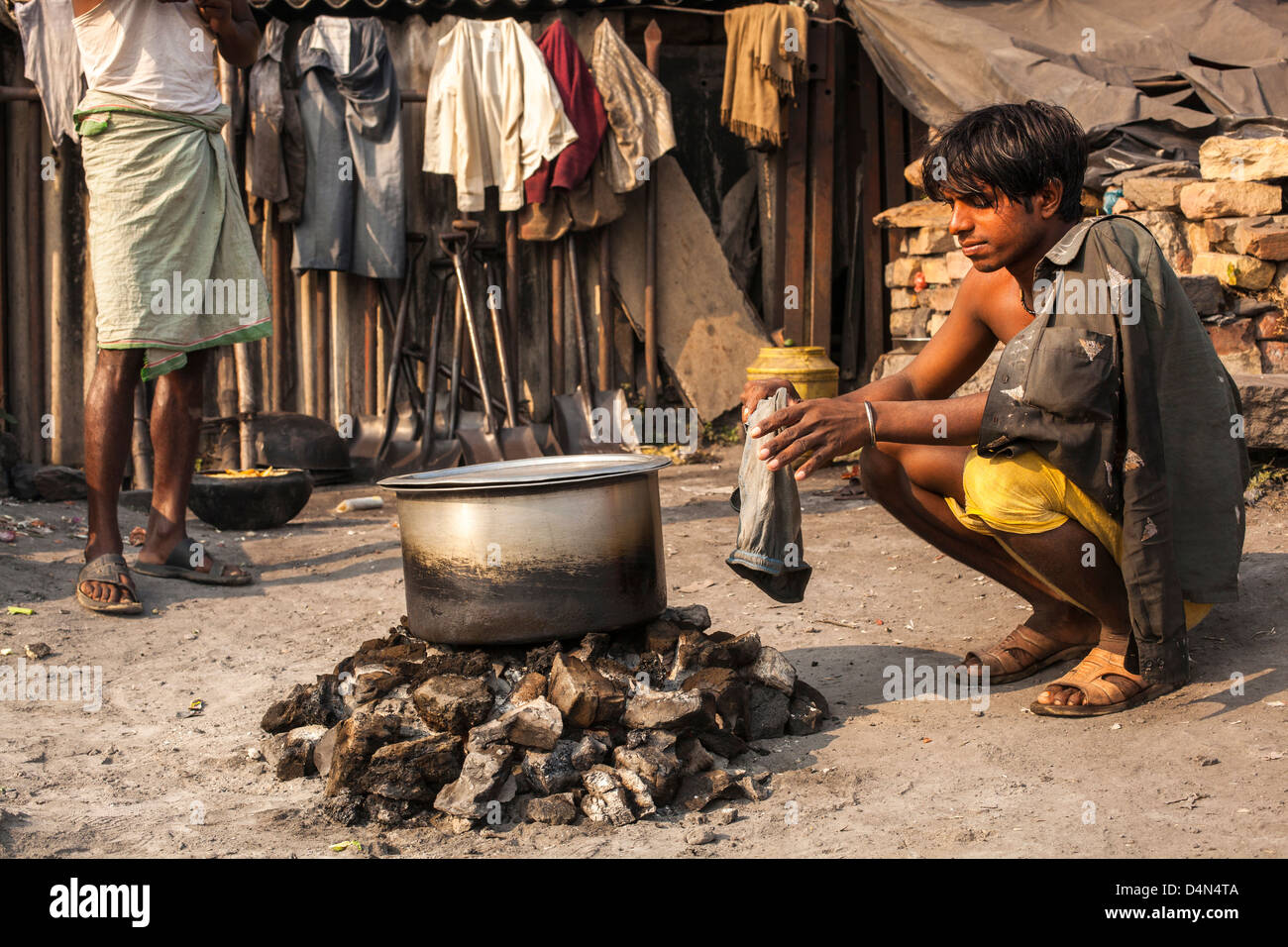 Obrero calentándose por brasas , Varanasi, India Foto de stock