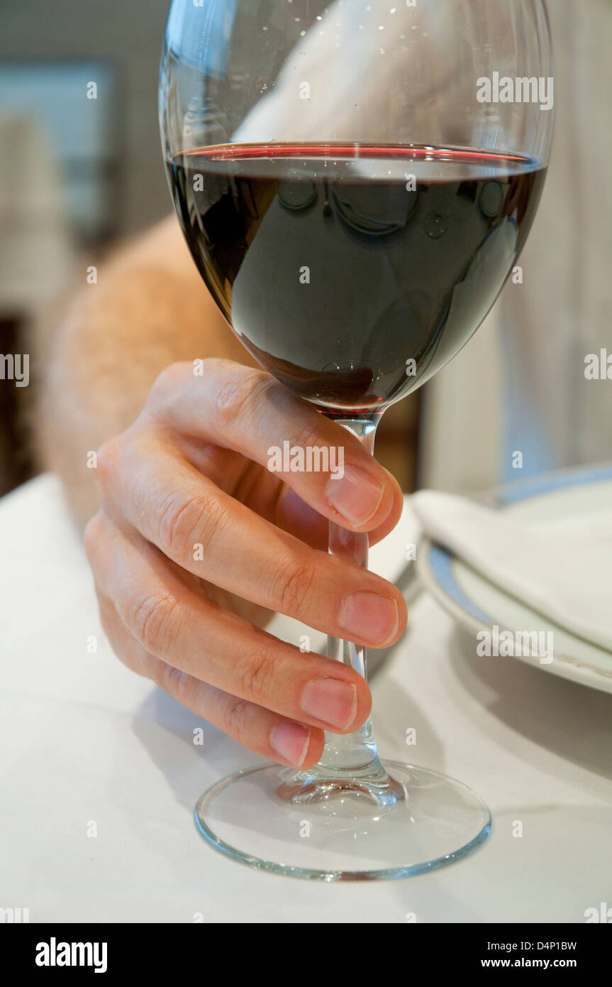 Sucediendo frágil Ocurrir La mano del hombre con un vaso de vino tinto. Cerrar vista Fotografía de  stock - Alamy